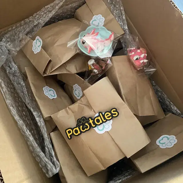 Caja llena de bolsas de papel selladas con el logo de PawTales, listas para abrir